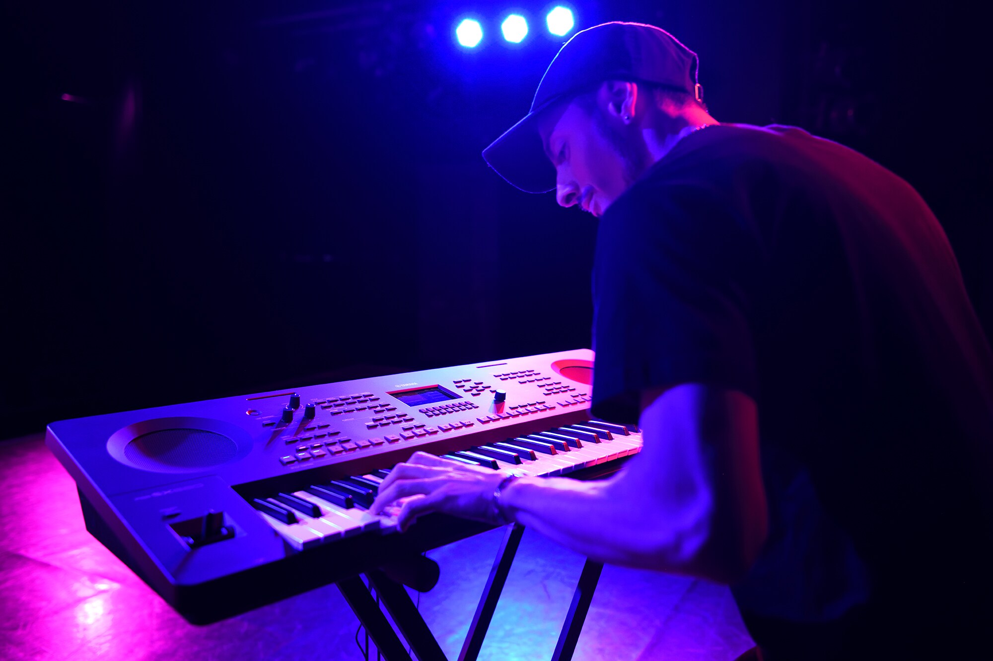 Uma pessoa a tocar uma arranger workstation Yamaha num suporte sob iluminação de palco
