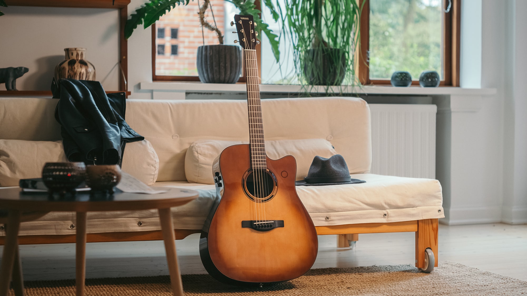 TAG3 C acoustic guitar placed on a sofa with a bag beside it.