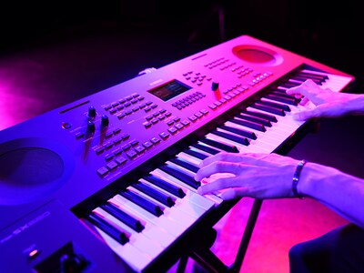 Grande plano de mãos a tocar um teclado durante uma atuação ao vivo.