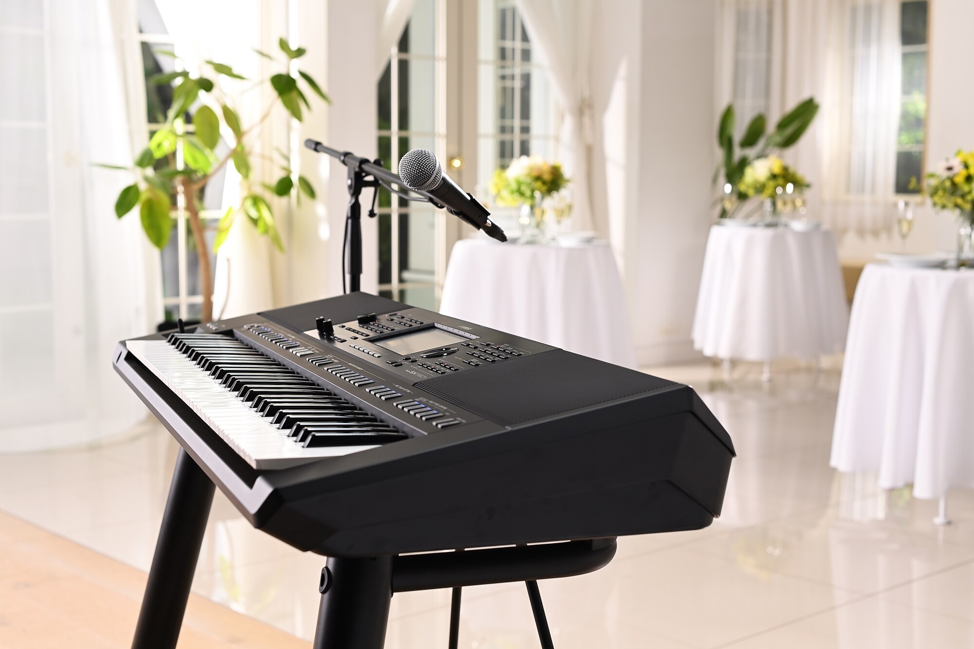Yamaha Arranger Workstation PSR-SX720+ com suporte de microfone num espaço de eventos