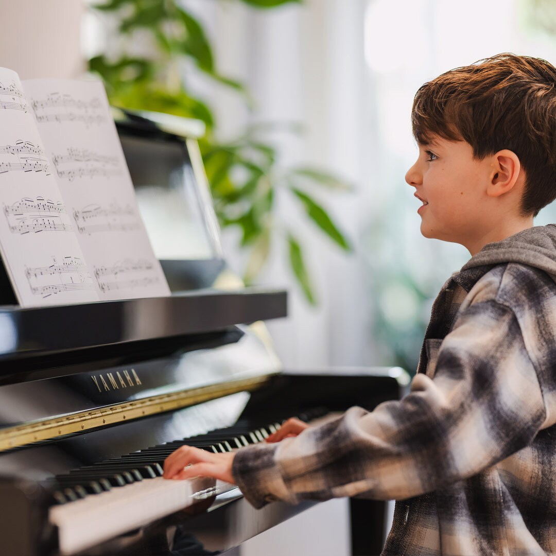 Uma criança desfruta ao tocar o piano vertical da Série B