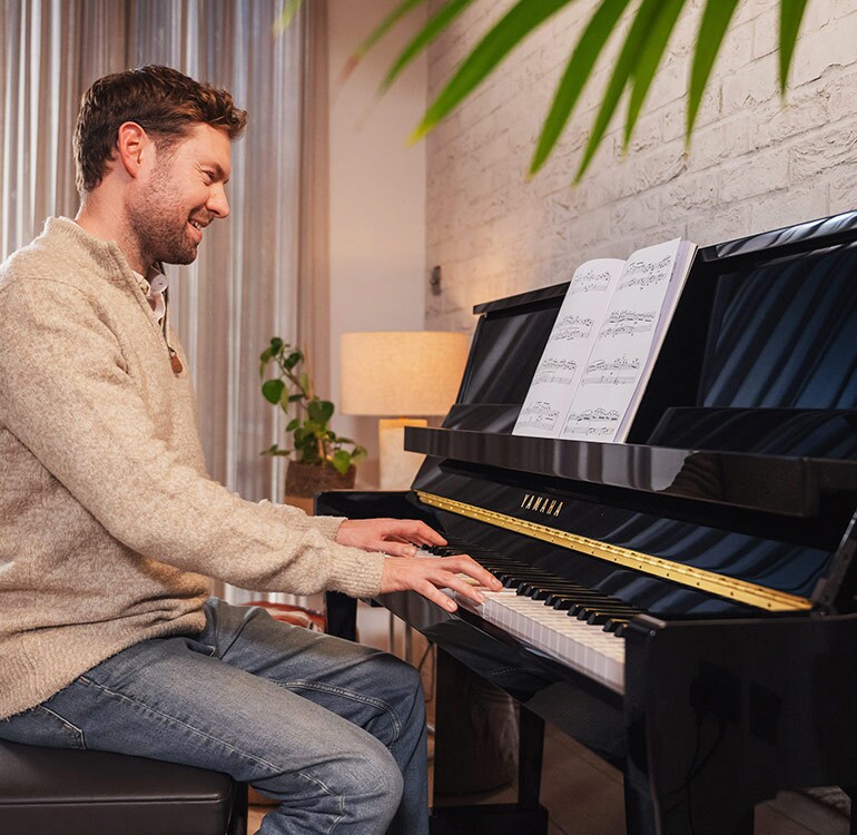 Uma mulher desfruta ao tocar o piano vertical da Série B