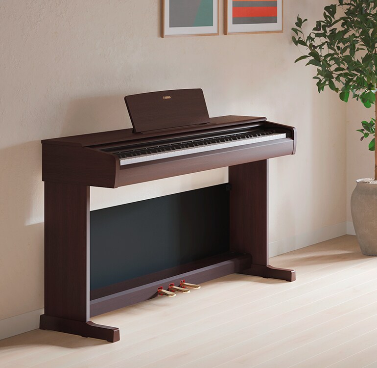 Uma sala de estar com um piano ARIUS, plantas de interior e um sofá, integrado harmoniosamente na decoração
