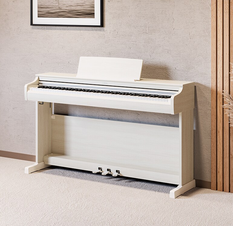 Uma sala de estar com um piano ARIUS em branco bétula, plantas de interior e um sofá, integrado harmoniosamente no espaço.