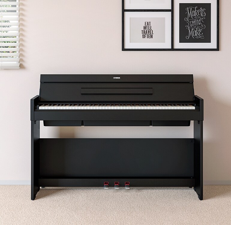 Uma sala de estar com um piano ARIUS em preto, colocado junto a prateleiras de parede com candeeiros e um difusor, integrado harmoniosamente na decoração