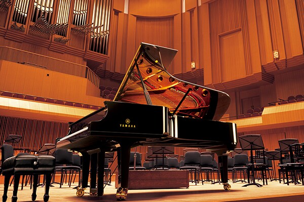 Piano de cauda de concerto Yamaha CFX num palco de sala de concertos.