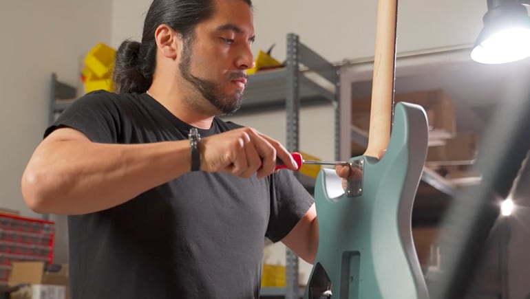 Guitar luthier assembling Yamaha electric guitar.